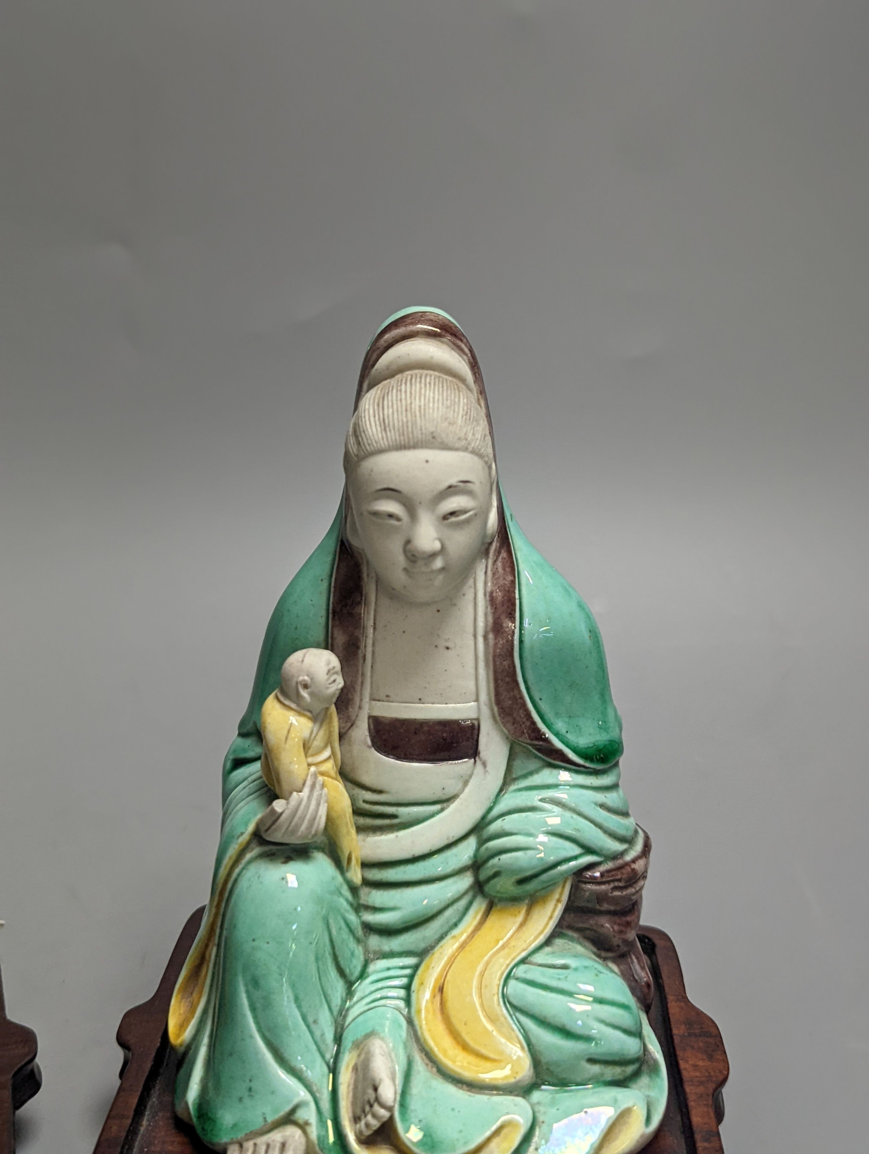 An 18th century Chinese sancai biscuit group of Guanyin with child and a 19th century Chinese sancai figure of Lu Dongbin, associated hardwood stands. 16cm